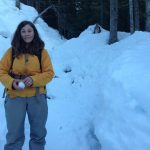 Woman with snowball in hand on mountain forest trail