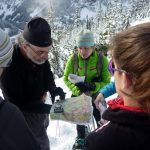 Studying a map while winter hiking on mountain trail